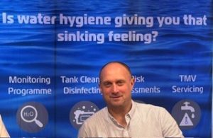 Phil White, Director of Irrigonics, in front of a water hygiene services banner